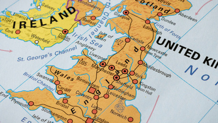 A close up of the UK and Ireland maps on a globe, with the land masses coloured in orange and yellow and key roads shown in red.
