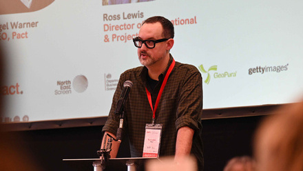Ross Lewis stood behind a lectern and microphone talking to an audience of Pact delegates at Content Without Borders 2026.