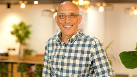 Headshot: Roy Ackerman, a bald man wearing glasses and a checked shirt. 