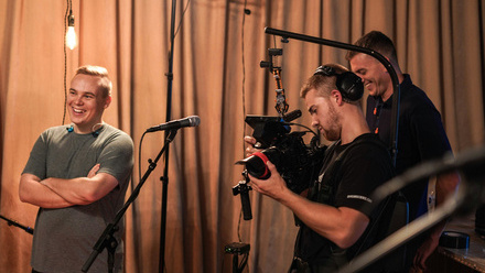 Production crew collaborating on set in front of a curtain background.