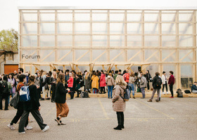 A large crowd of people walking around outside a building.
