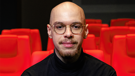 Headshot: Chris Filip, a man with a bald head and glasses wearing a black turtleneck jumper.