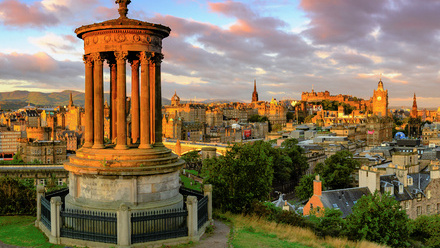 Photo of the Edinburgh skyline at dusk, with purple-pink clouds on an otherwise blue sky.