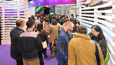 A group of producers networking at a trade show booth at FILMART Hong Kong.