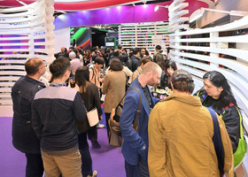 A group of producers networking at a trade show booth at FILMART Hong Kong.
