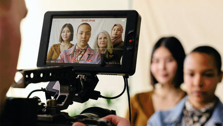 Photo taken behind a camera monitor showing four women of different ethnic backgrounds looking directly into the camera.