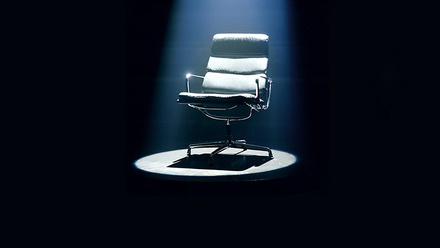 Mastermind hot seat chair under a spotlight with a dark background.
