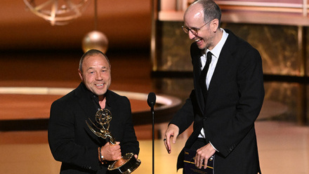 Jack Thorne and Stephen Graham dressed in black tie on stage at the Emmys accepting an award.