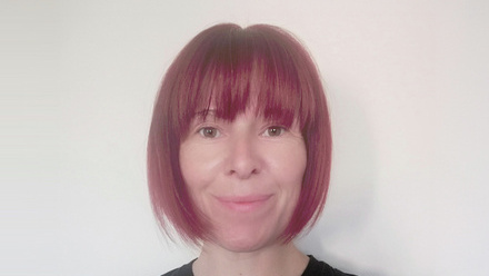 Headshot; Gemma Wilans, a woman with a short, red bob and fringe wearing a black top.