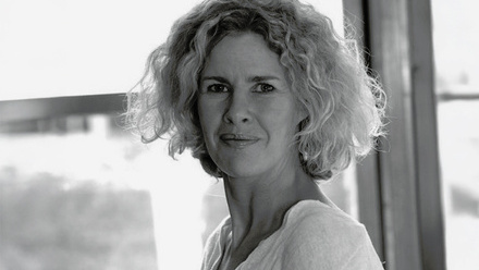 Headshot: Kirstie McLure, a woman with short, blonde, curly hair wearing a blouse.