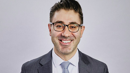 Headshot:  Karnig Dukmajian, a man with dark brown hair and glasses wearing a suit and tie.