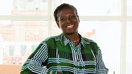 Headshot: Ade Rawcliffe, a woman with short, dark hair wearing a green, checked shirt.