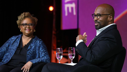Two speakers on stage at the Prime Time 2025 conference sat in front of a purple background.