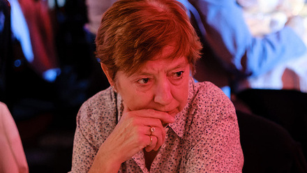 Headshot: Ann McManus, a woman with short brown hair wearing a patterned shirt, gazing out of frame right.