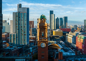 Image of downtown Manchester with a mix of modern and old buildings and the iconic Kimpton clocktower in the centre.