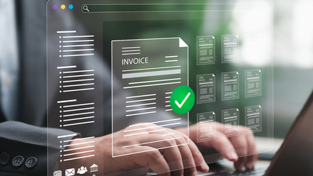 Person typing on laptop with digital invoice approval interface and green check mark overlay.
