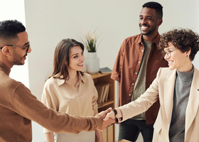 Four people making a deal with two people shaking hands.