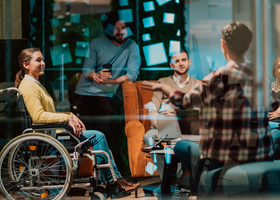 A diverse group of people in the workplace having a conversation and looking engaged.