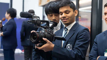 Two students operating a camera in a school setting. 