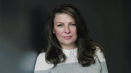 Headshot: Deborah Dunnett, a woman with long, dark brown hair styled to the side wearing a grey jumper.