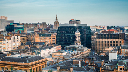 A rooftop view of the mixed architecture of old and new buildings in Glasgow city in late afternoon light.