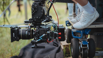 Close-up of camera operator shooting low angle grass on a production set.