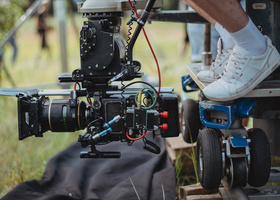 Close-up of camera operator shooting low angle grass on a production set.