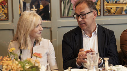 Nigel Warner talks to Tracy Brabin at a table with breakfast items in a bright wood-panelled room.