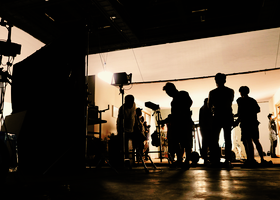 Crew members in silhouette against a lit stage.