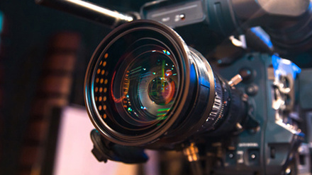 Filming camera lens with colourful reflections in a studio setting.