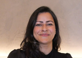 Headshot: Anushka Sinha, a woman with long dark hair wearing a black top.