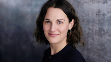 Headshot: Samantha Hornsby, a woman with short, dark brown hair and hoop earrings wearing a black top.