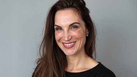 Headshot: Atlanta Webster, a woman with long dark-brown hair swept to the side wearing a black top.