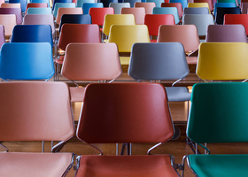 Photo: Multicoloured chairs are lined up in rows about six wide and five deep.