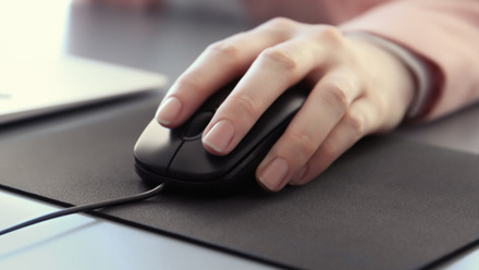 Close-up of a hand on a black computer mouse, on a black mouse pad.