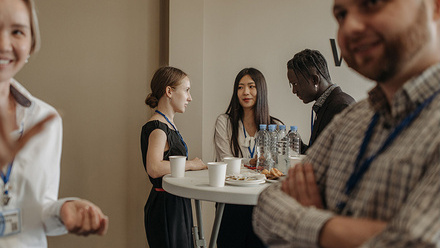 A diverse group of professionals networking during a business event with refreshments.