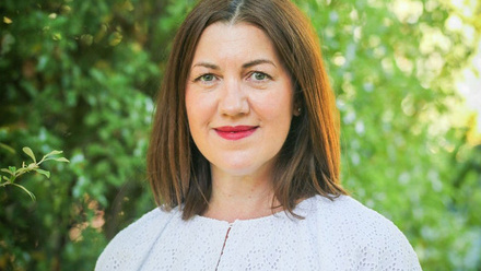 Headshot: Jayne Edwards, a woman with shoulder-length straight hair, wearing red lipstick and a white top.