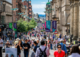 Photograph of a sunny day in Glasgow with people walking up and down Buchanan Street.