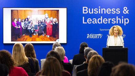Speaker presenting to an audience in front of a blue background reading 'Business & Leadership' at FOCUS conference 2024.