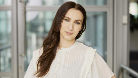 Headshot: Alisa Pomeroy, a woman with long, wavy brown hair swept over one shoulder wearing a white shirt.