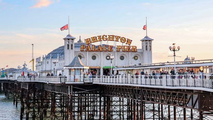 Landscape image of Brighton Pier in front of a blue sky. 